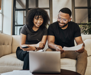 young couple looking at a laptop together on the sofa